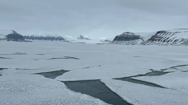 Montañas cubiertas de nieve y hielo agrietado sobre el mar.