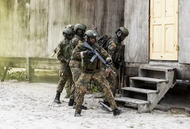 Soldados guyaneses caminan en actitud vigilante y esgrimen sus armas durante un ejercicio.