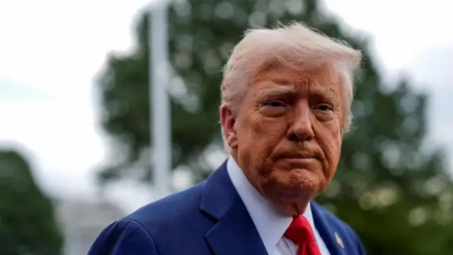 Donald Trump, presidente de EE.UU., con un traje azul y una corbata roja viendo a la cámara