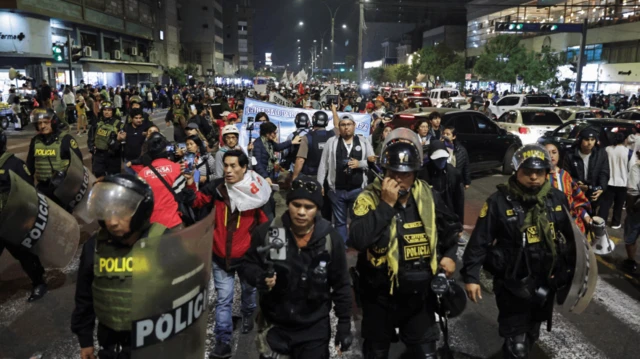 Agentes de policía caminan junto a los manifestantes que participan en una marcha organizada por el colectivo juvenil