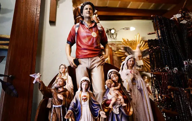 Una figura de Acutis junto a varias de la virgen María y una de San Francisco de Asís.