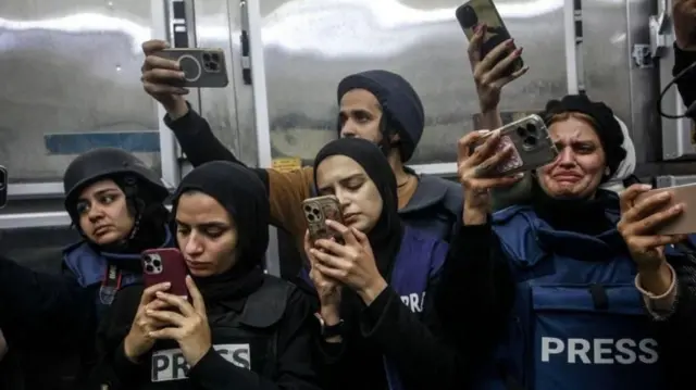 Un grupo de periodistas con chalecos azules que dicen PRENSA con celulares en las manos