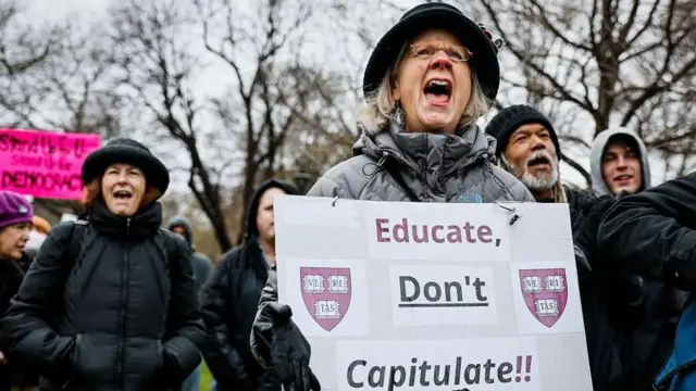 Protesta en Harvard con una mujer con un cartel que dice: Educa, No Capitules