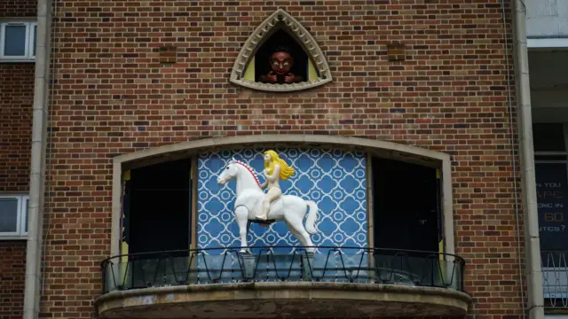 La figura de Godiva en un reloj que se mueve cada hora y la figura de un anciano viendola desde arriba