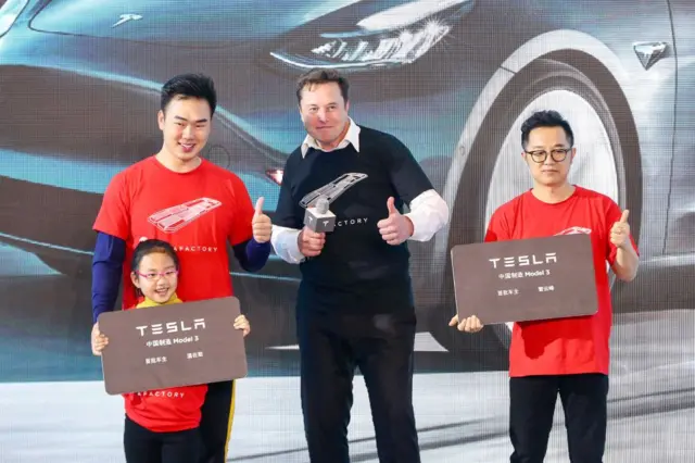 Elon Musk (C) posa para las fotos con los compradores durante la ceremonia de entrega del Model 3 fabricado en China en Shanghái