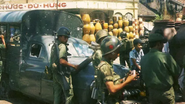 Imagen de varios soldados en las calles de saigón. Se ve jimmy al fondo sentado entre los militares.