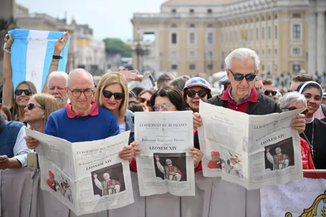 Feligreses y turistas revisan la edición especial del diario vaticanista L'Osservatore Romano.
