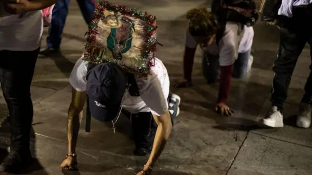 Devotos, agachados a gatas sobre el piso, con la imagen de la virgen a sus espaldas