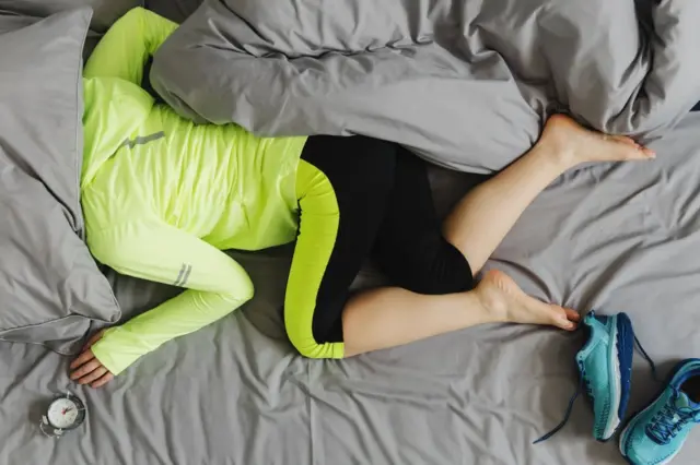 Mujer vestida para hacer ejercicio dormida en la cama