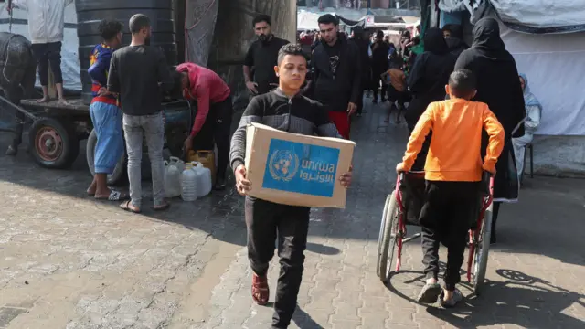 Un joven palestino carga una caja de asistencia distirbuida por UNRWA en  Deir al-Balah, Gaza central (4 de noviembre 2024)