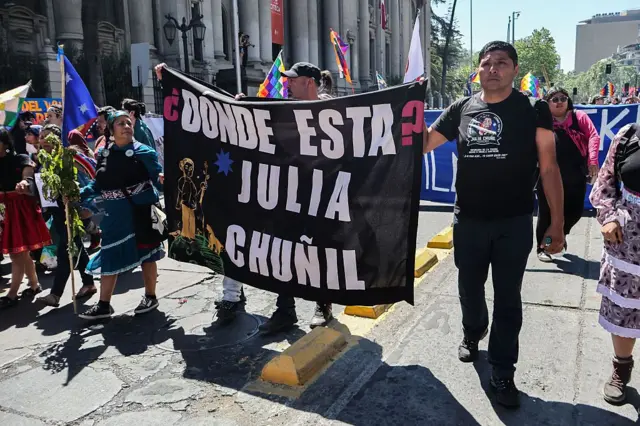 Pablo San Martín Chuñil, hijo de Julia Chuñil, sostiene una bandera que dice 
