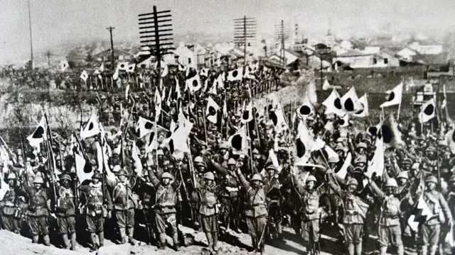 Tropas japonesas levantan los brazos y ondean banderas en Nanjing tras la conquista de la ciudad en 1937.