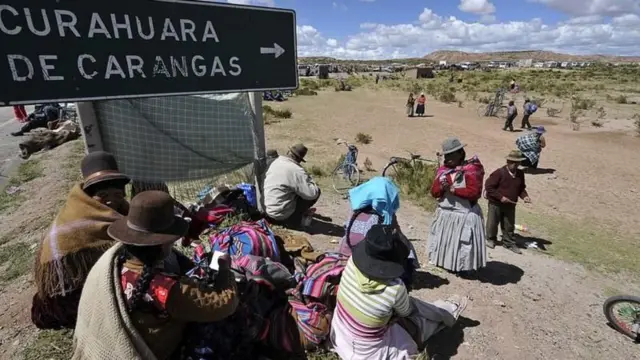 Personas pertenecientes a los aymara caminan por un poblado largo.