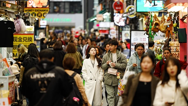 Gente caminando por una concurrida calle comercial.