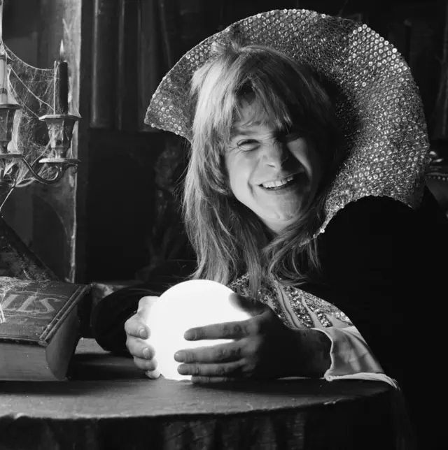 Ozzy Osbourne sostiene una bola de cristal vestido con una túnica de mago. 