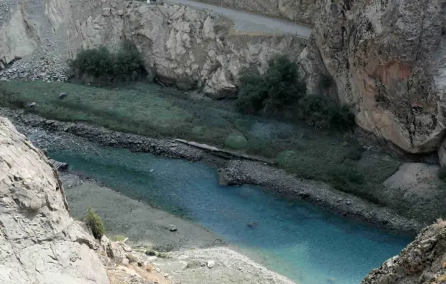 Una vista desde arriba de la presa Amir Kabir, uno de los cinco principales embalses que abastecen de agua a Teherán, el 29 de julio de 2025: una cresta de piedras sobresale del centro de un lago con paredes escarpadas, donde no hay agua y la vegetación crece en las áreas secas alrededor del agua.