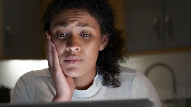 Una mujer estresada mirando la pantalla de una laptop
