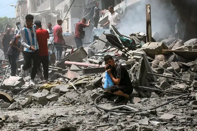 Un grupo de palestinos entre los escombros tras un ataque israelí en Ciudad de Gaza.
