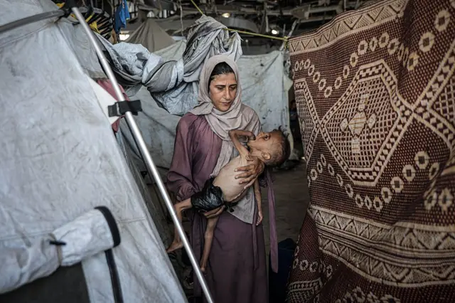 Muhammad Zakariya Ayyoub al-Matouq junto a su madre en una tienda de campaña, en Gaza. 