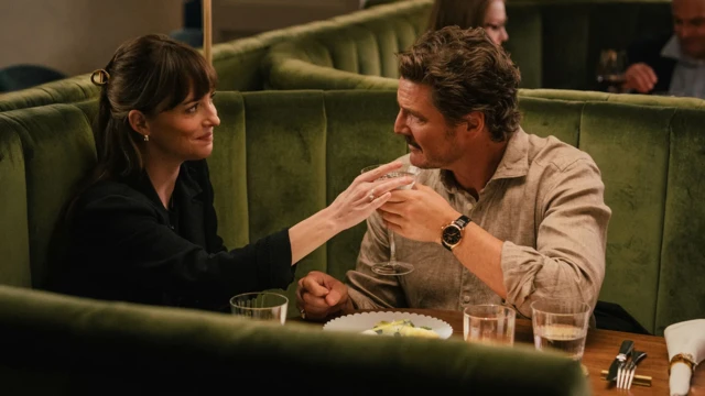 Una pareja heterosexual se mira a los ojos mientras está sentada a la mesa en un restaurante. La mujer posa su mano en una copa de martini que sostiene el hombre.