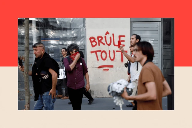 Manifestantes pasan junto a una pintada que propone 