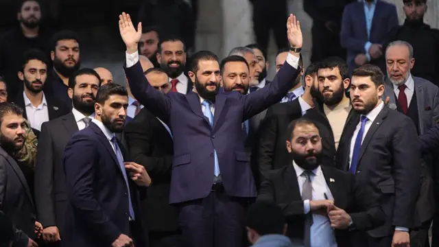 El presidente sirio Ahmed al Sharaa saluda a la multitud en la puerta de la Ciudadela de Alepo durante las celebraciones que conmemoran el primer aniversario de la entrada de una alianza islamista, liderada por Sharaa, en la ciudad norteña y la rápida toma del control, el 29 de noviembre de 2025.