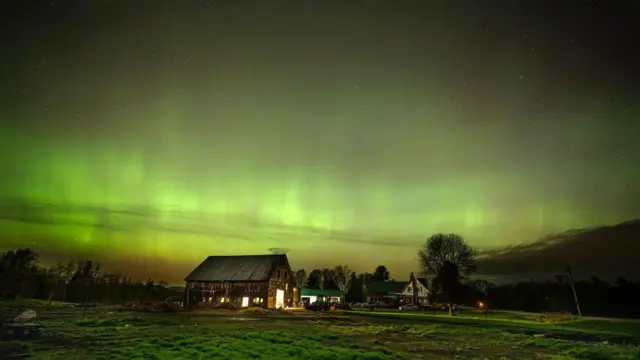 Una casa con el cielo verde de auroras boreales.