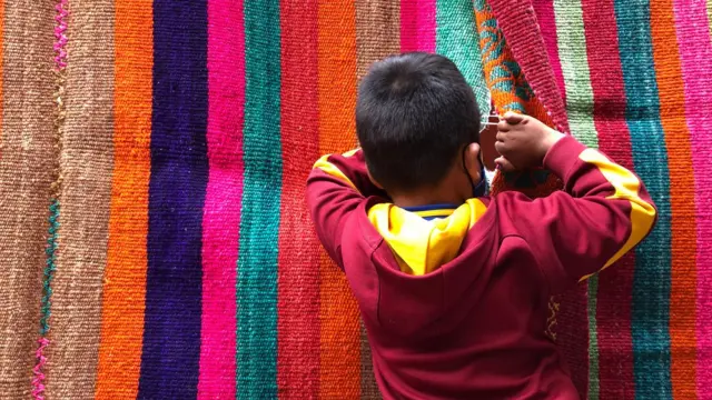 Un niño espía por el agujero de una manta. 