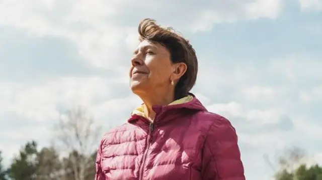 Una mujer inhala al aire libre.