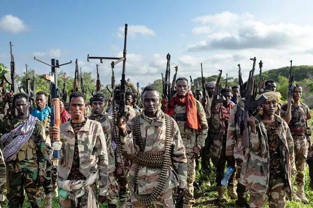 Un grupo de soldados somalíes de pie con sus armas apuntando al cielo. 