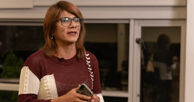 Azul Rojas da una charla de pie y con un teléfono entre las manos. 