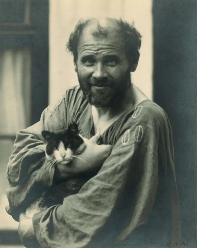 Gustav Klimt mira a la cámara mientras carga un gato en sus brazos