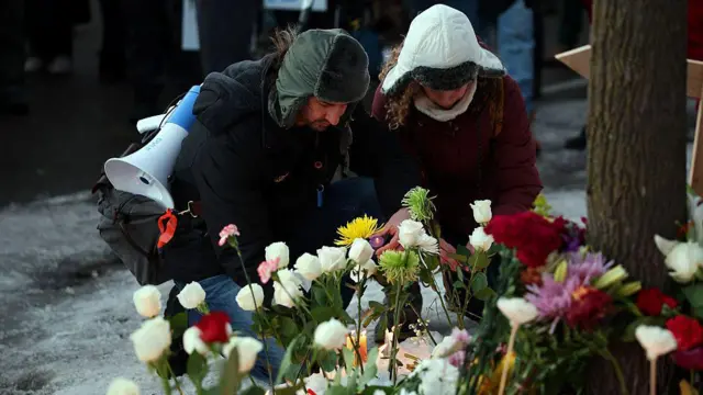 Un hombre y una mujer agachados colocan flores en honor a Renee Nicole Goods, quien falleció a tiros a manos de un agente federal durante una redada migratoria en Mineápolis, Minesota, Estados Unidos, el 7 de enero de 2026. (Foto: David Berding/Getty Images)