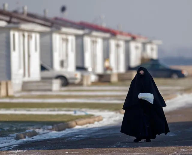 Miembro de la comunidad Lev Tahor, presumiblemente una mujer, completamente tapada de los pies a la cabeza. Solo se le ven los ojos. Camina por una calle con nieve. 