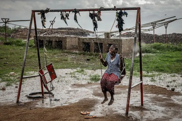 Una joven refugiada congoleña juega en un columpio bajo una fuerte lluvia mientras los refugiados esperan ser reubicados en el Centro de Tránsito de Cishemere, cerca de Buganda, el 6 de mayo de 2025.
