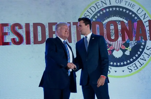 Donald Trump dándole la mano a Charlie Kirk.