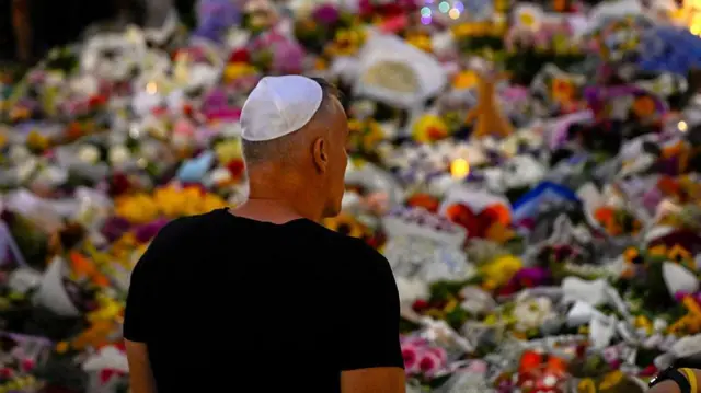 Hombre mira decenas de ofrendas florales.