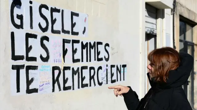 Gisèle lee una frase escrita en la pared en la que las mujeres le agradecen lo que hizo.