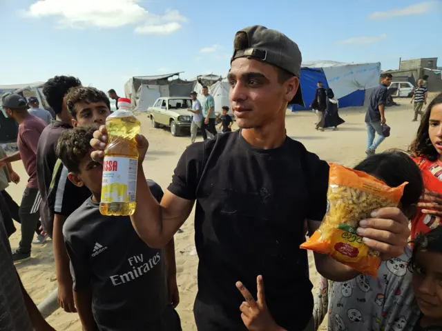Un chico palestino muestra una botella de aceite de cocinar y un kilo de pasta