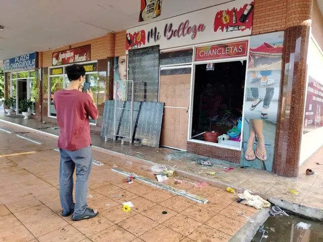 Una persona con un celular toma la foto de una tienda afectada