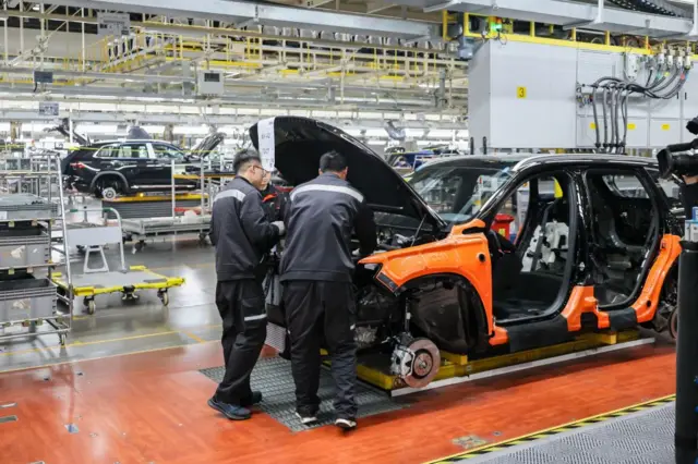 Empleados trabajan en la línea de ensamblaje de vehículos eléctricos (VE) Smart en la base de fabricación de automóviles de Geely el 12 de diciembre de 2024 en Xi'an, provincia de Shaanxi, China.