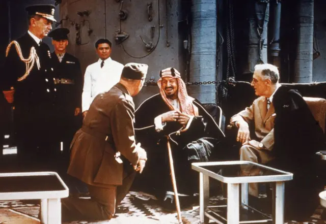 El presidente estadounidense Franklin Delano Roosevelt reunido con el rey Ibn Saud de Arabia Saudita, el jefe de Estado Mayor William D. Leahy (de rodillas) y el coronel William A. Eddy, a bordo del USS Quincy en el Canal de Suez, Egipto, el 14 de febrero de 1945. 