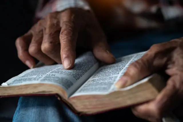 La manos de una persona de color sobre una Biblia
