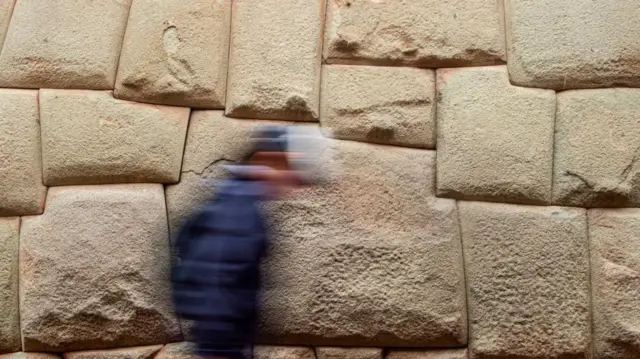 Un hombre pasa junto a la piedra de los 12 ángulos. 