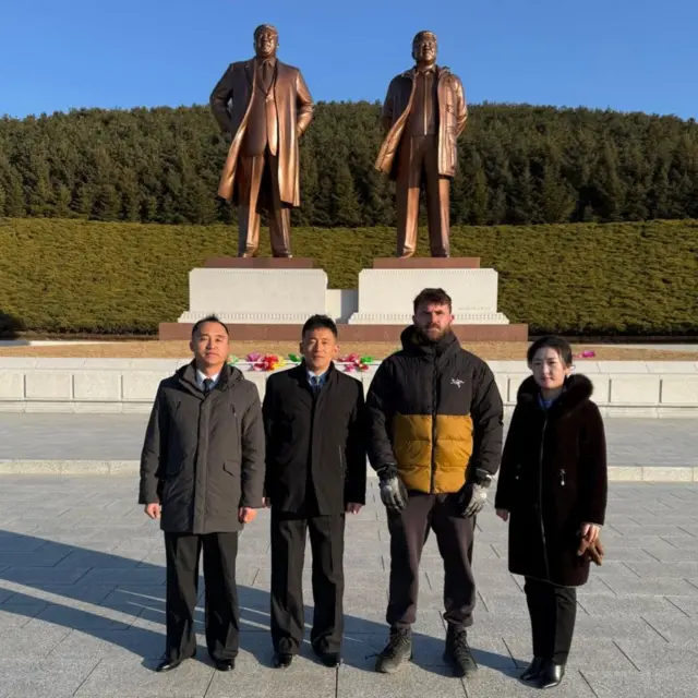 Turista frente a estatuas de los líderes