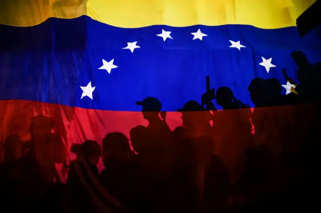 Bandera venezolana con personas vistas a contraluz