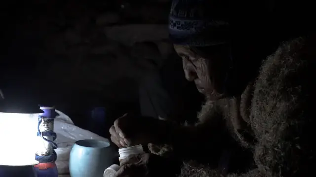 Persona iluminada con una linterna mientras se sirve un té en el poblado de Pampa Clemesí, sur de Perú.