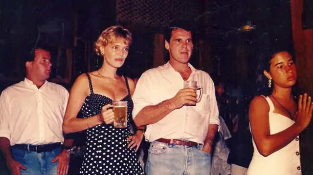 En lo que parece ser un bar, Annette y Willem sostienen una cerveza mientras miran a un costado, ambos en la misma dirección. A su alrededor, otras personas.