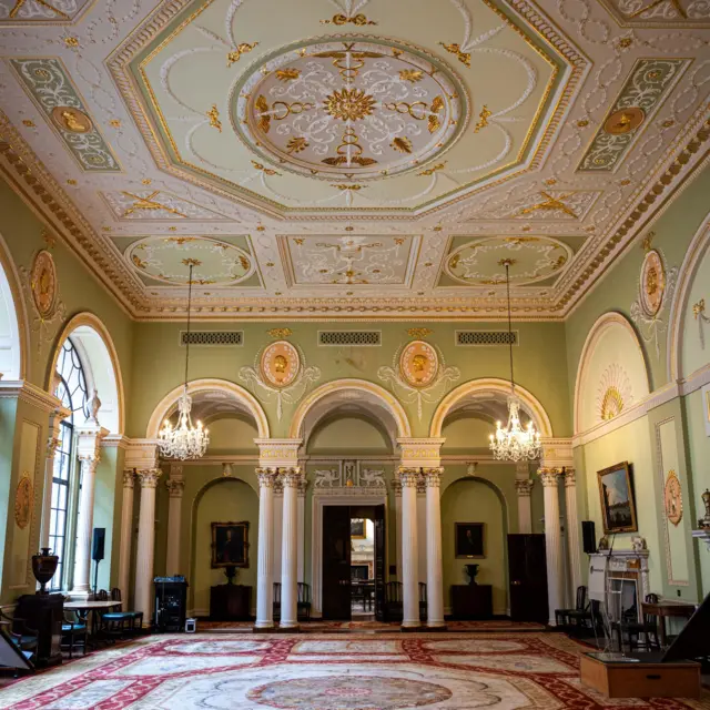 Uno de los salones del Banco de Inglaterra con columnas y paredes verdes.