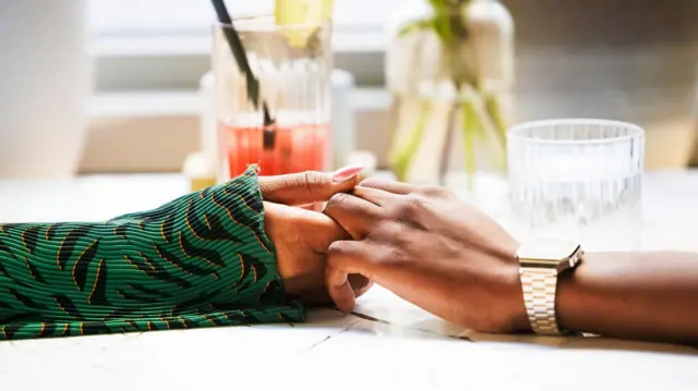 La mano de una mujer y de un hombre se tocan en una mesa